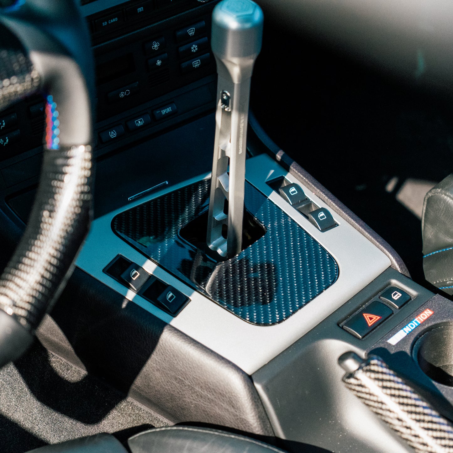 Close-up of a car's gear shift lever with carbon fiber pattern