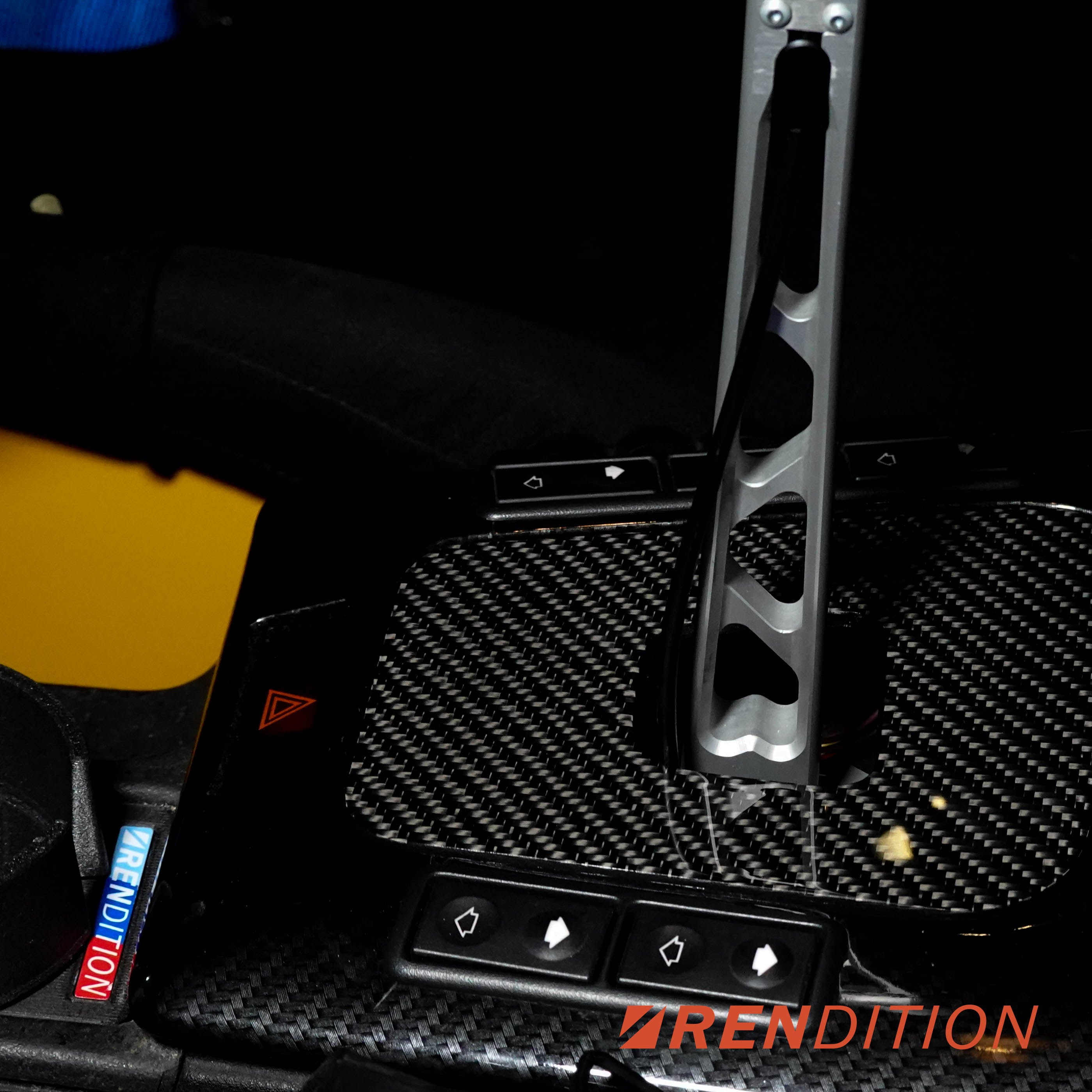 A black BMW E36 shift boot cover with a carbon fiber finish, installed in a vehicle's interior.